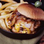 A French onion burger served with fries and olives.