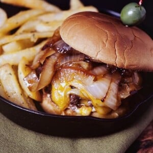 A French onion burger served with fries and olives.