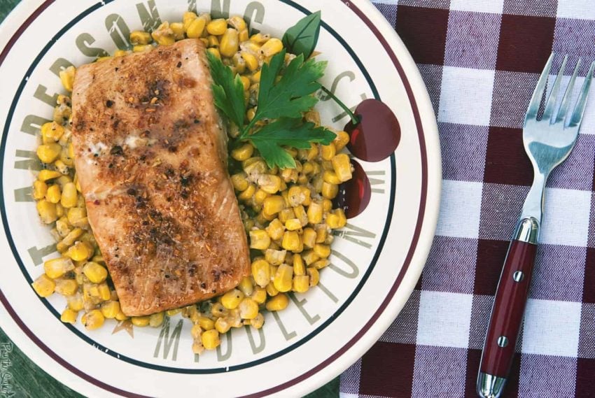 Overhead platter of oven baked salmon on a plate with corn. 