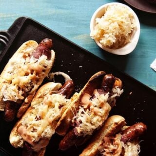 Reuben hot dog with sauerkraut and mustard on a tray.