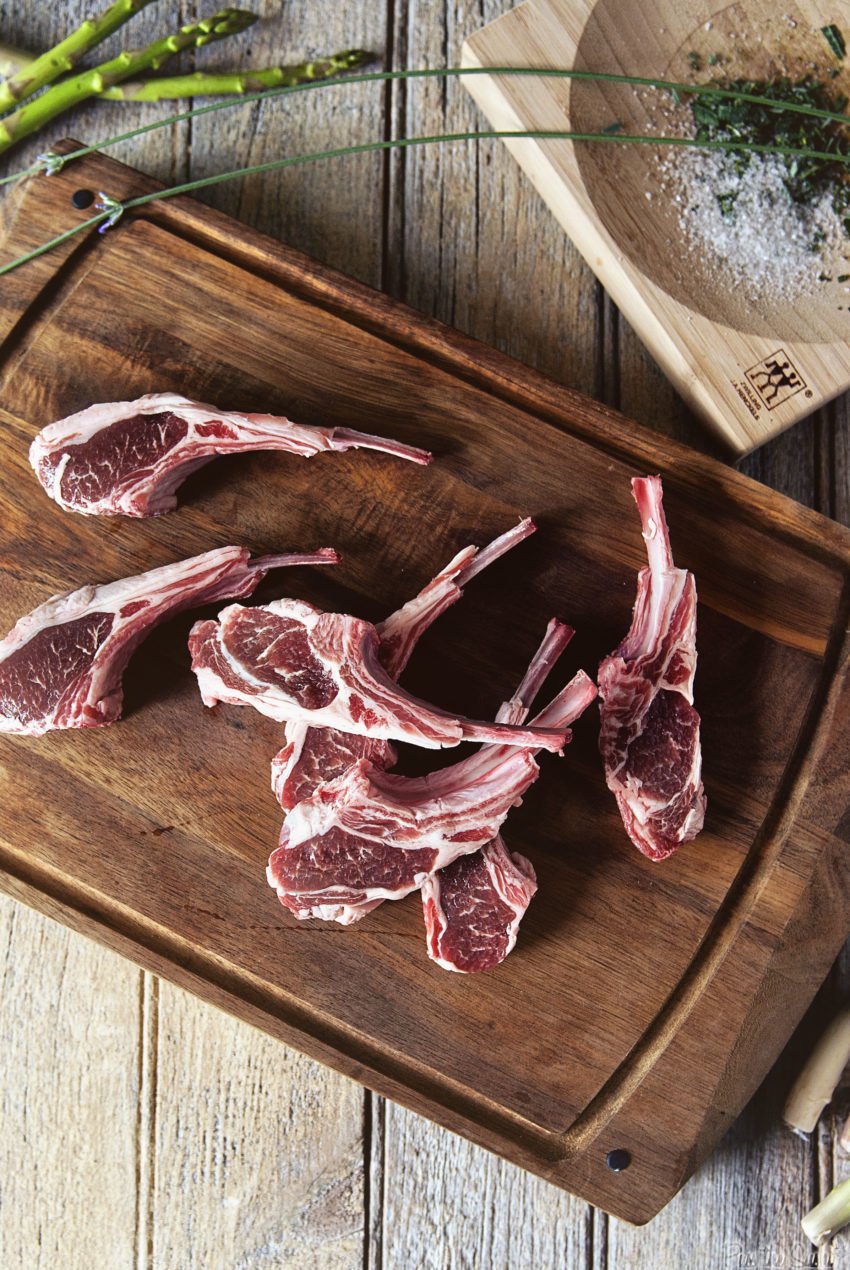 Lamb chops on a cutting board, patted dry and ready for salting.