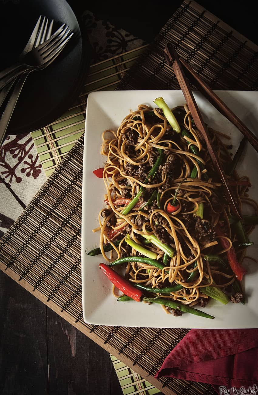 Szechuan beef noodles with vegetables on a white plate 