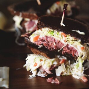 A corned beef sandwich served on a wooden plate.
