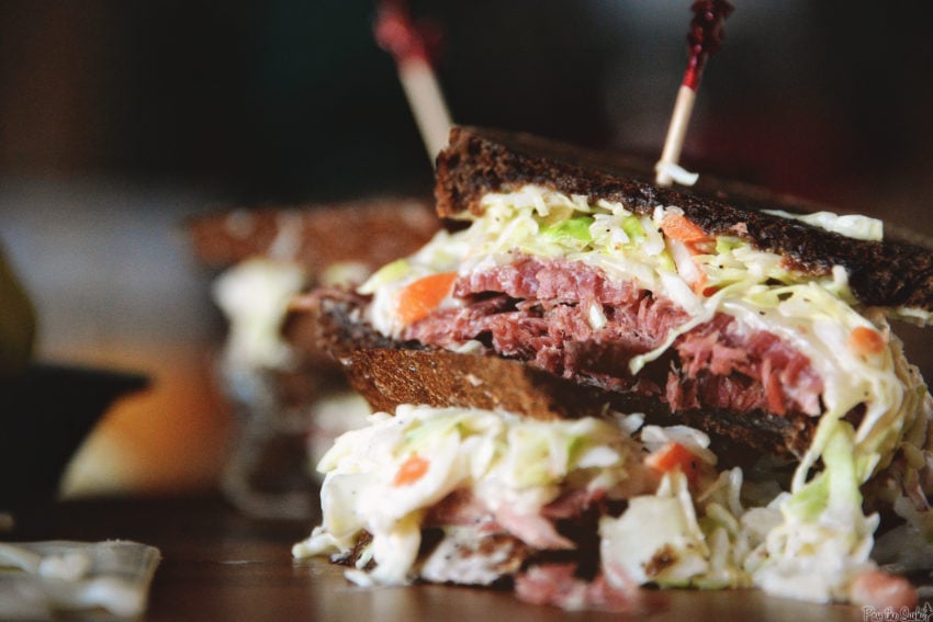 Close up of corned beef sandwich with slaw and shaved corned beef. 