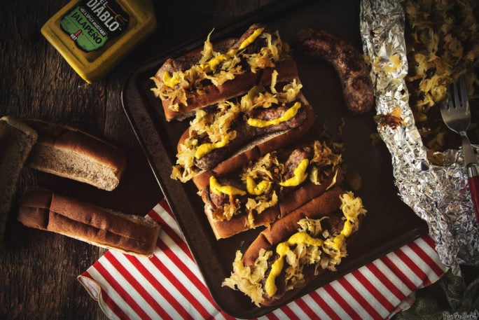 Four plump brats just loaded up with Spicy Mustard and Sauerkraut. Grab a plate, it's go time!