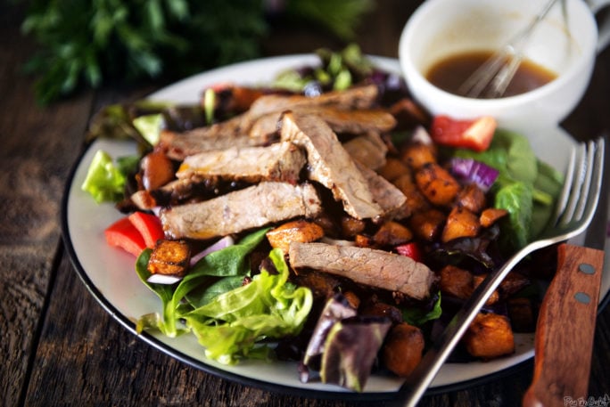 Slices of New York Strip piled on top of salad greens, sweet potatoes, and veggies. So good!