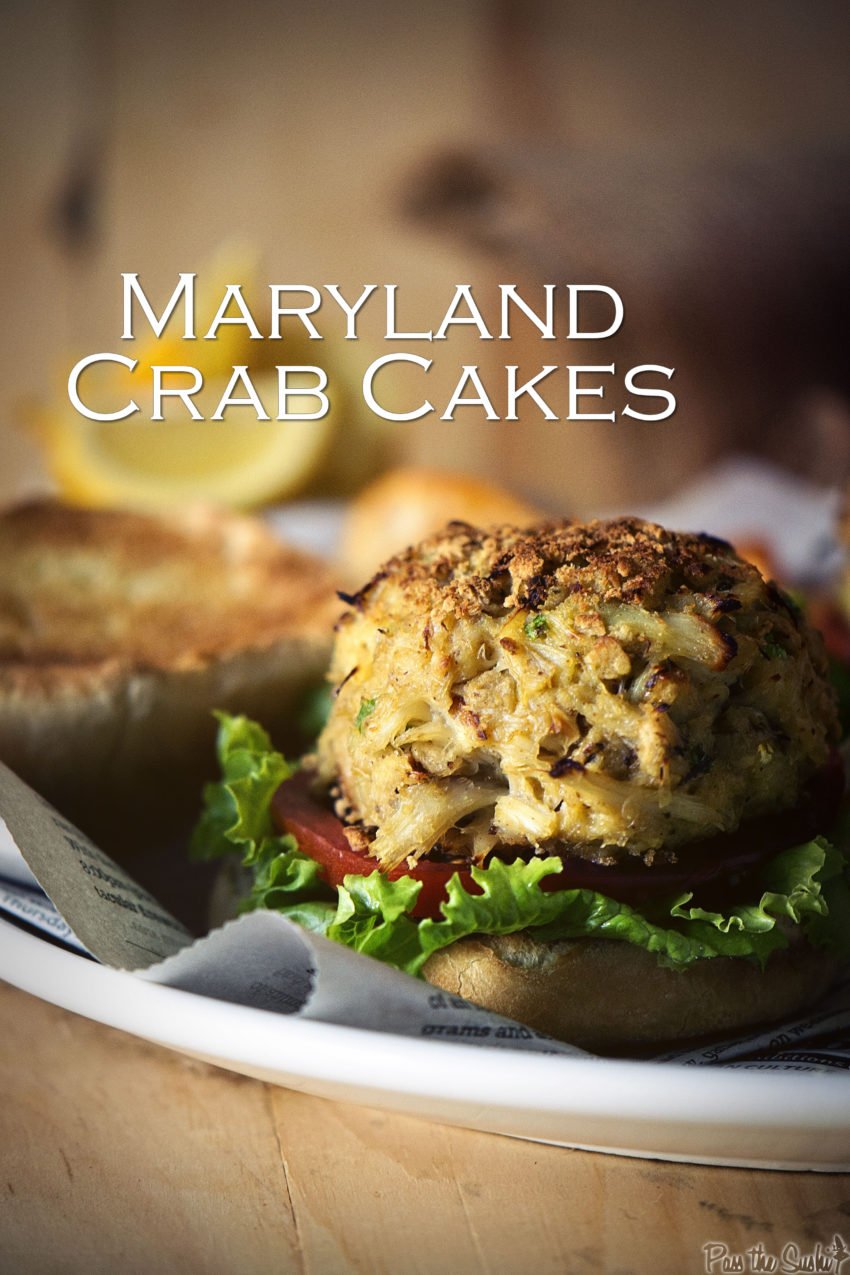 close up of a maryland crab cake showing flakey jumbo lump crab meat  nestled on a bun with lettuce and tomato.
