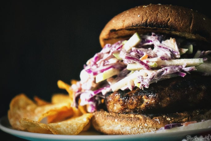 Apple-Brat Burger with coleslaw on top. Served with chips and ready to be devoured.