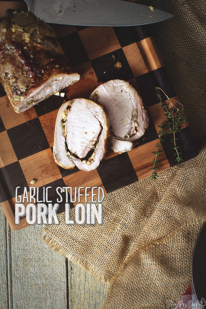 Overhead shot of a sliced stuffed pork roast on a cutting board. 