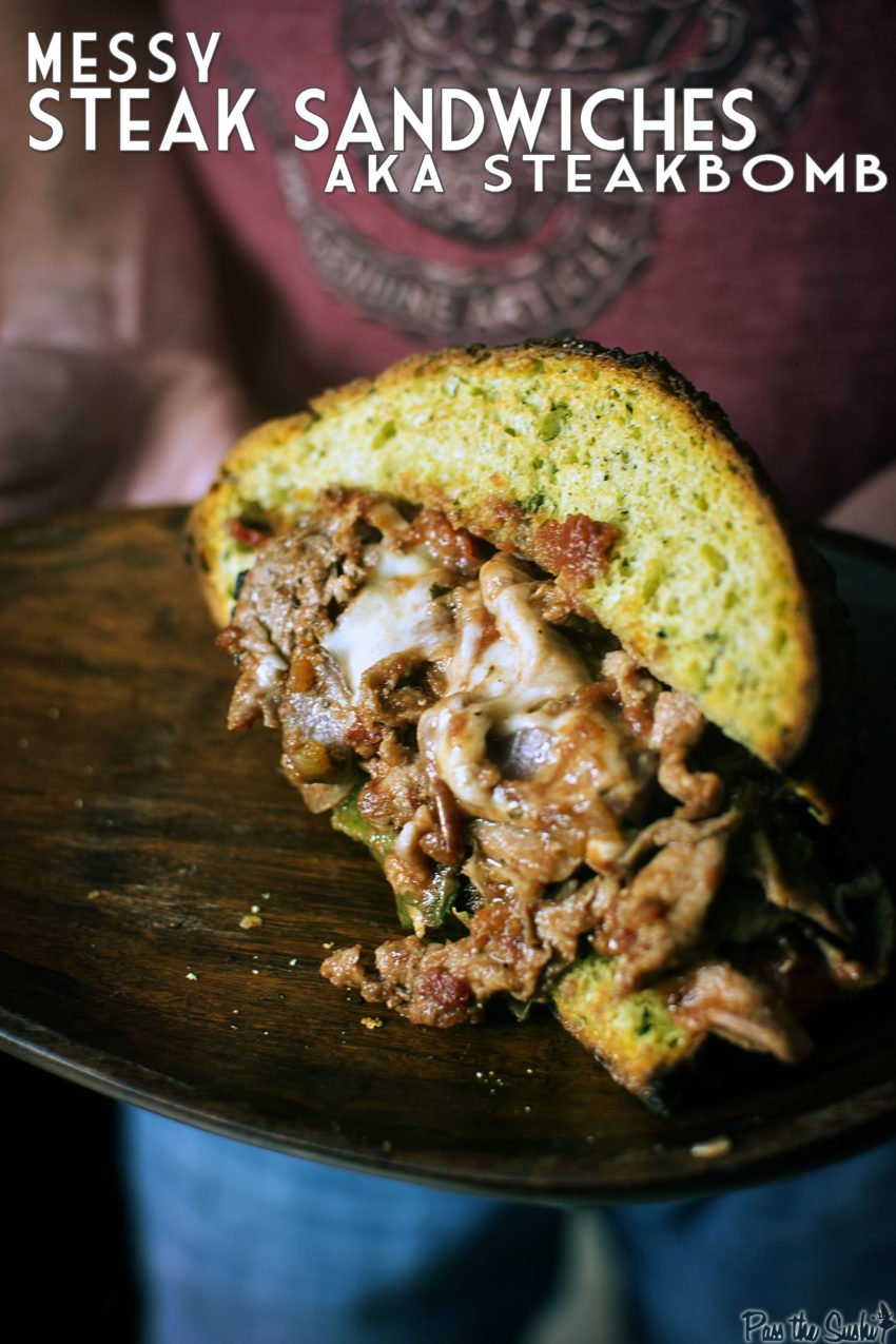 Hands holding the messy steak sandwich on a plate. 