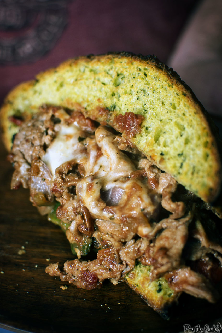 Up close of thin shaved beef and melted cheese on thick layers of focaccia bread. 