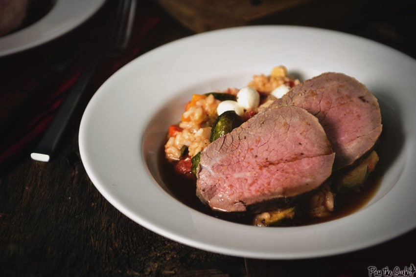 Two slices of eye of round roast over a fall roasted veggie risotto