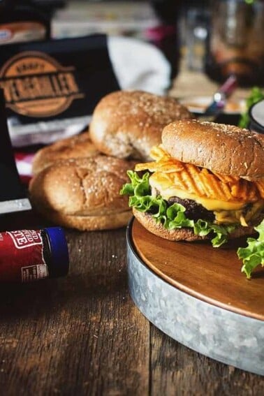 Barbecue burgers with a bottle of bbq sauce on a wooden table.