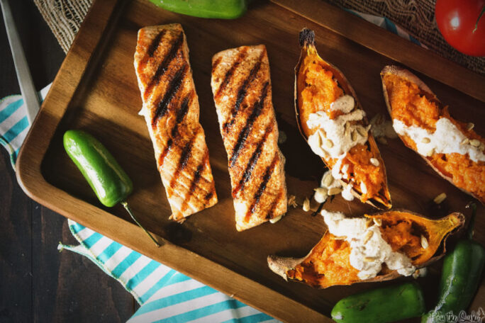 Ancho Rubbed Grilled Salmon with Nogada Sauce on wooden tray with chilis 