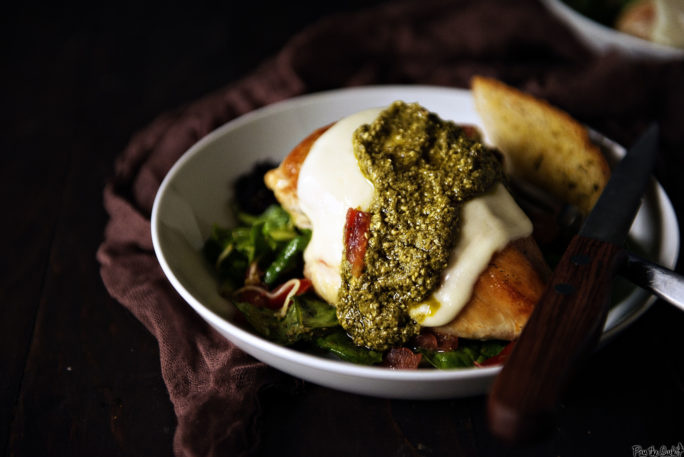 There is a pile of pesto topping this chicken breast. A slice of fresh Mozzarella, and we can see healthy eating can be pretty damn delicious.