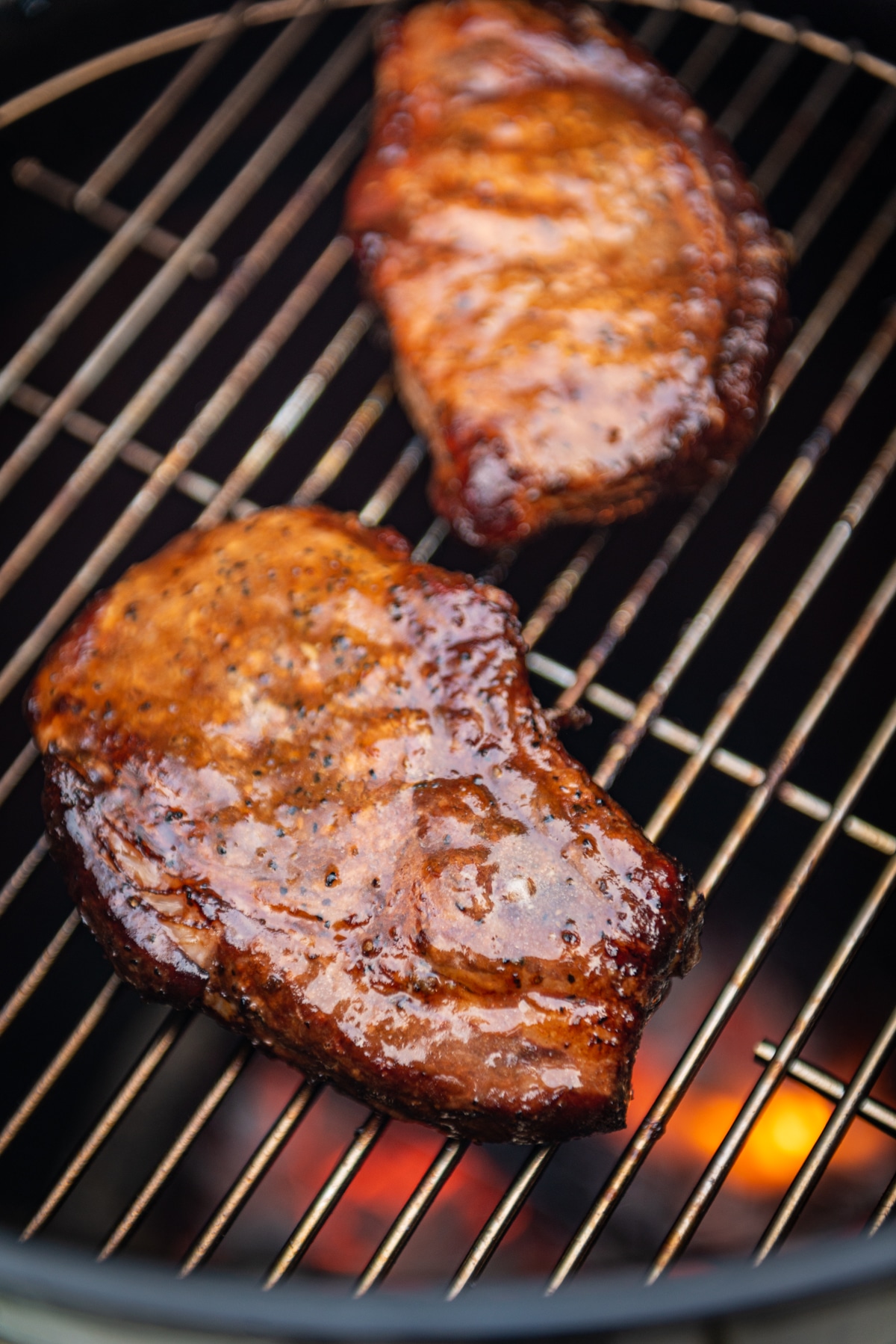 Pork chops finishing on the grill grate after being smoked.