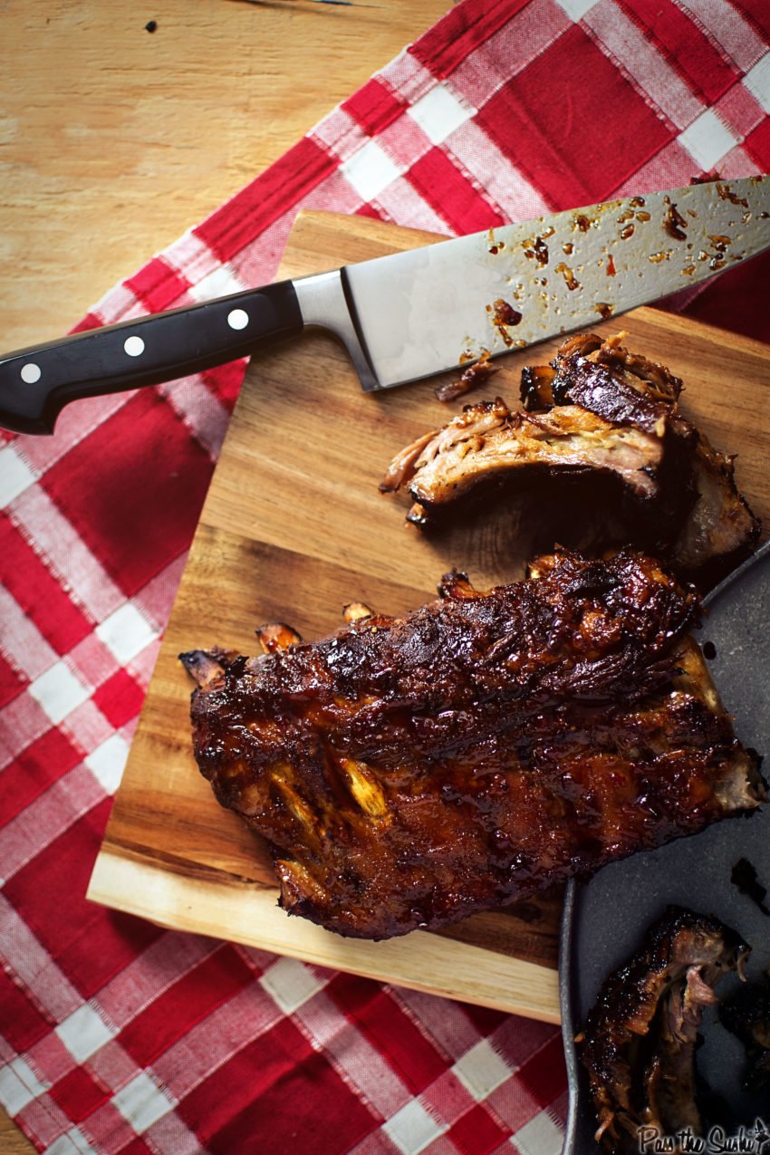 Pork ribs on a cutting board, with a knife. one rib cut to show tenderness 