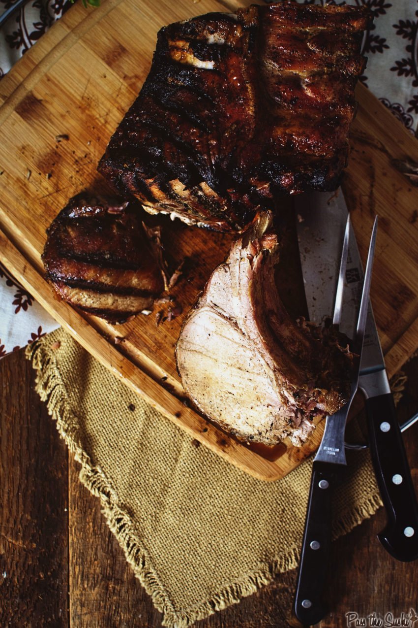 overhead shot of bone-in pork roast being sliced on a cutting board. 