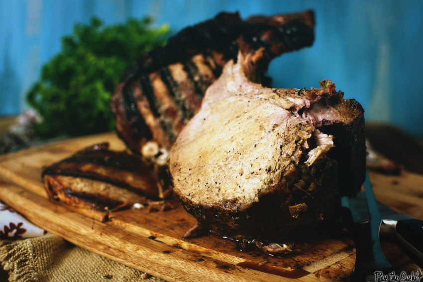 Grilled pork roast, sliced to show juicy center on a cutting board. 