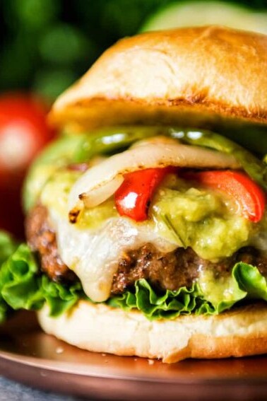 Fajita-inspired burger with guacamole and peppers on a plate.