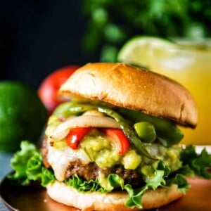 A Fajita Burger with guacamole, lettuce and tomatoes on a plate.