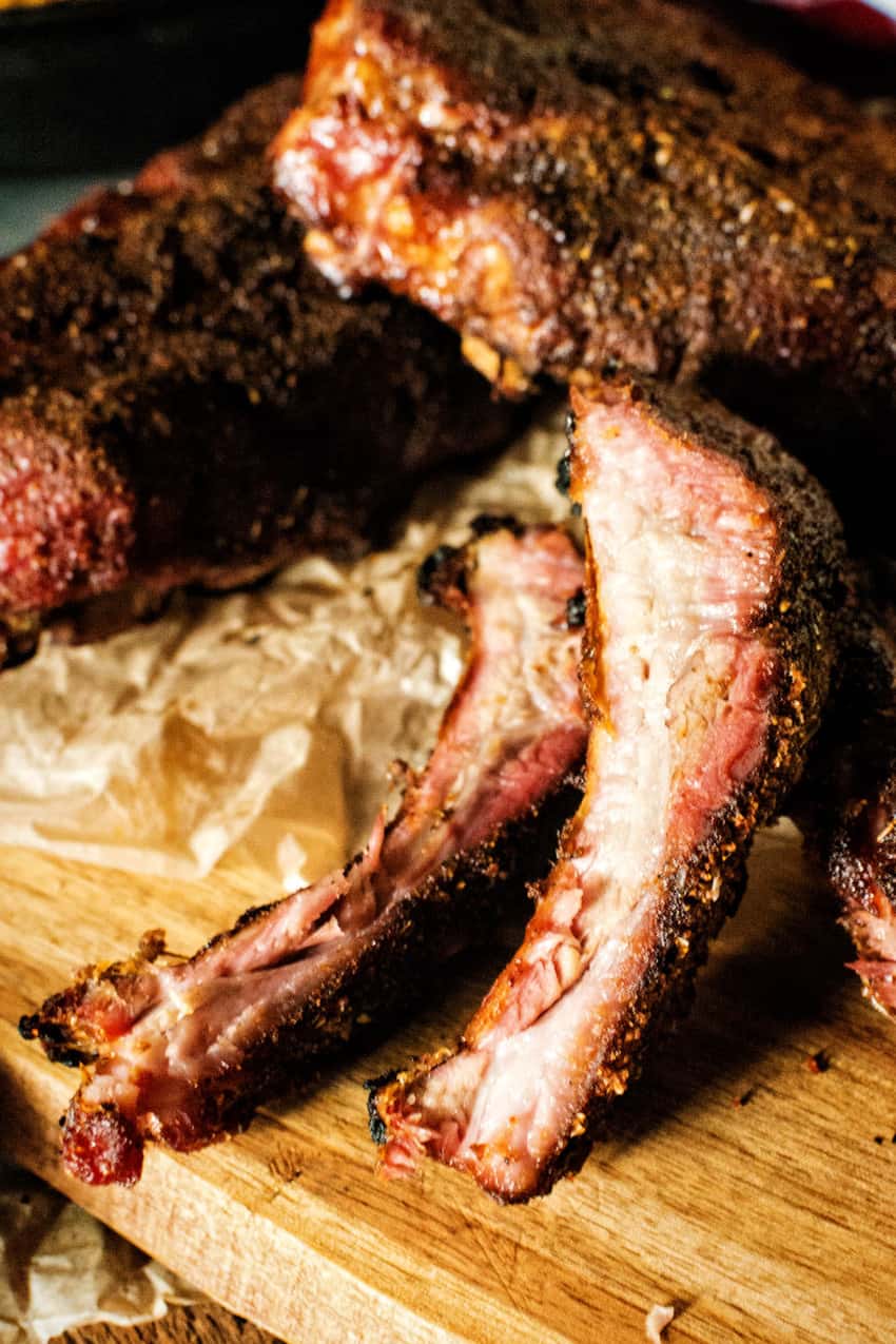 Close up of sliced pork ribs, showing a pink smoke ring and spiced bark. 