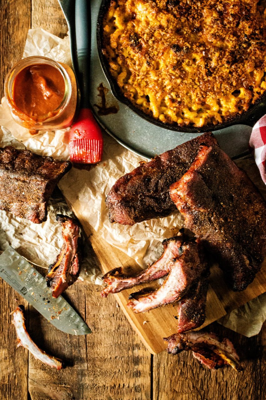 Overhead shot of platter of smoked ribs with mac and cheese and barbecue sauce.