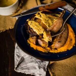 A plate with sausage and potatoes, topped with hearty gravy.