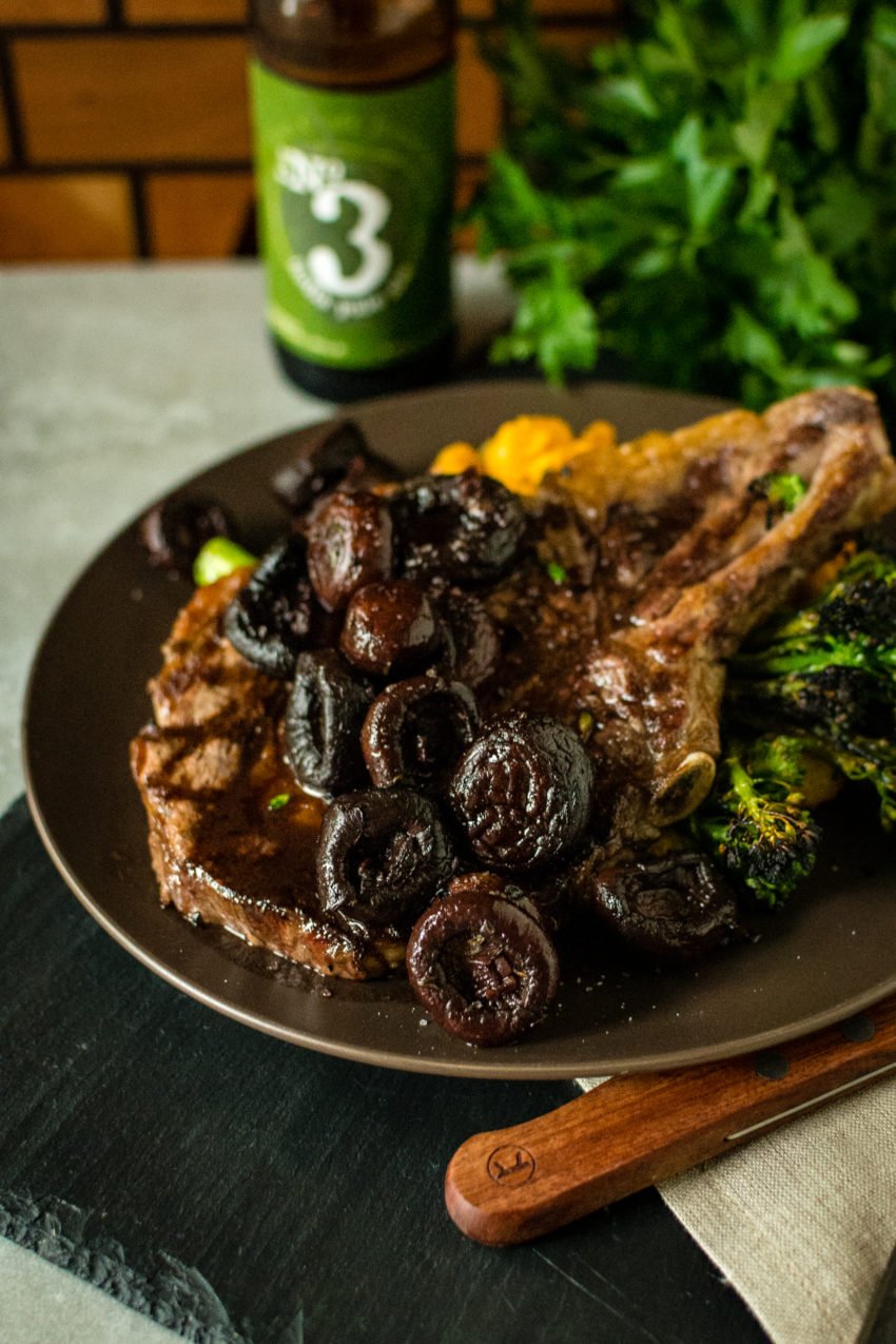 Steak with red wine sauce and mushrooms on a plate with veggies.