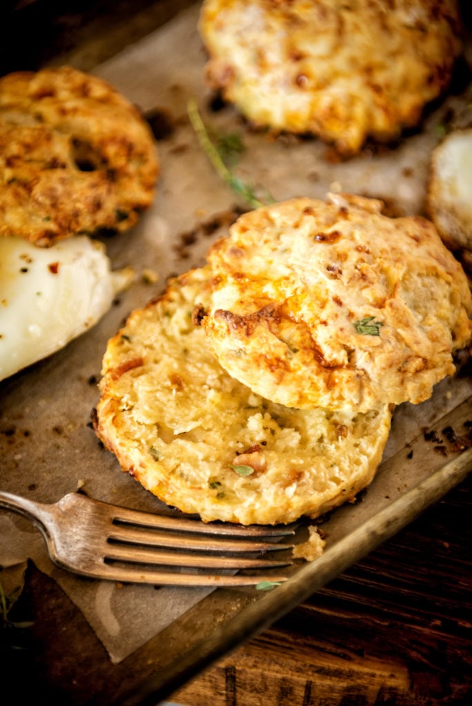 A cheesy buttery biscuit sliced in half. perfect crumbs and flecks of herbs.