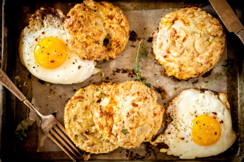 Herb and Bacon Cottage Cheese Biscuits with eggs on a sheet-pan. grab a fork.