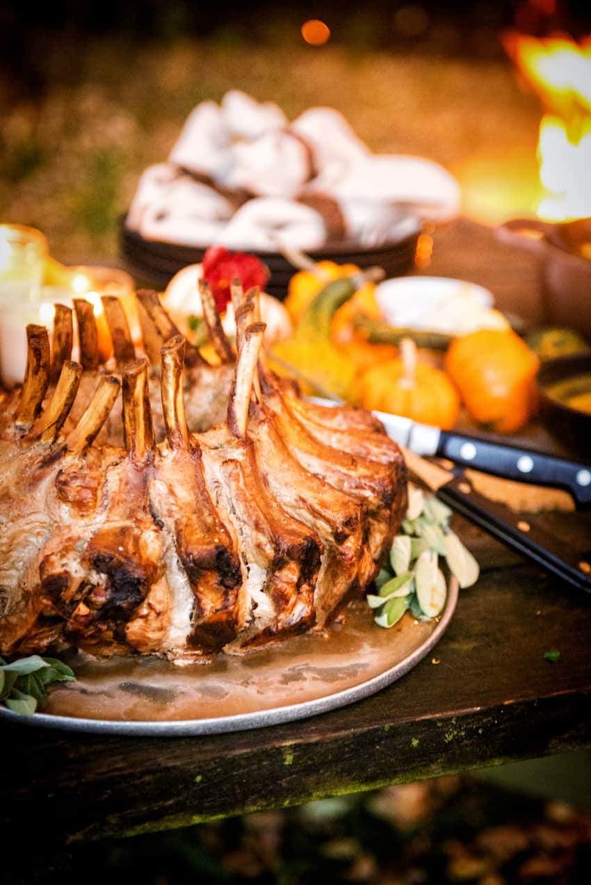 Smoked crown pork roast placed on a plate garnished with herbs.