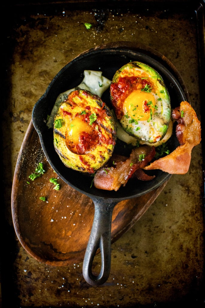 This split avocado has never looked better. Filled with two baked eggs, layered with Harissa, and packed in alongside some bacon, you're gonna like this breakfast!