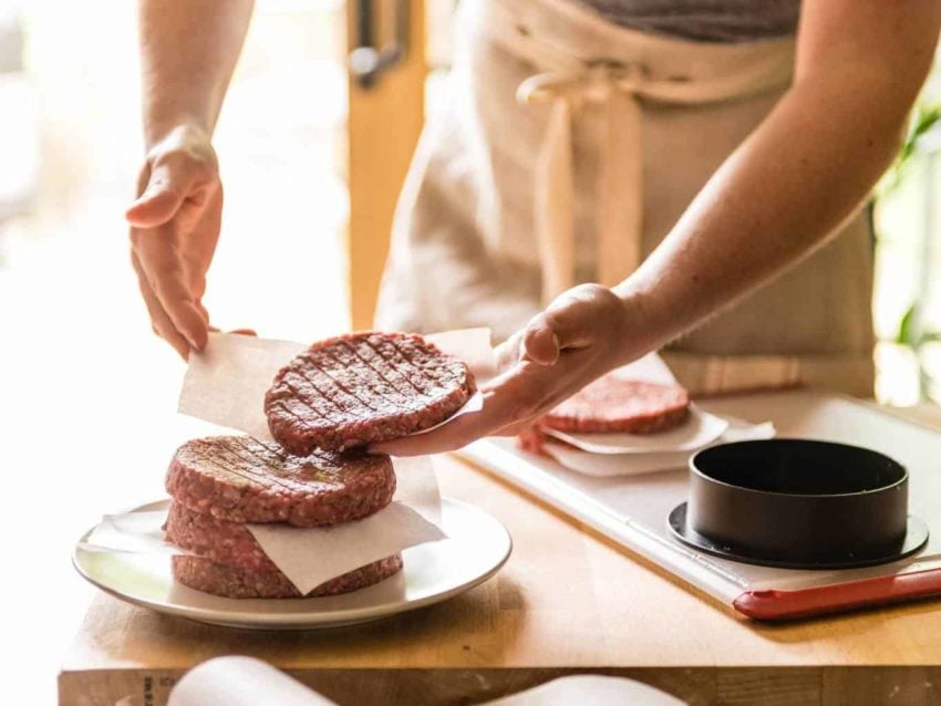 Hand placing formed patties in a stack.