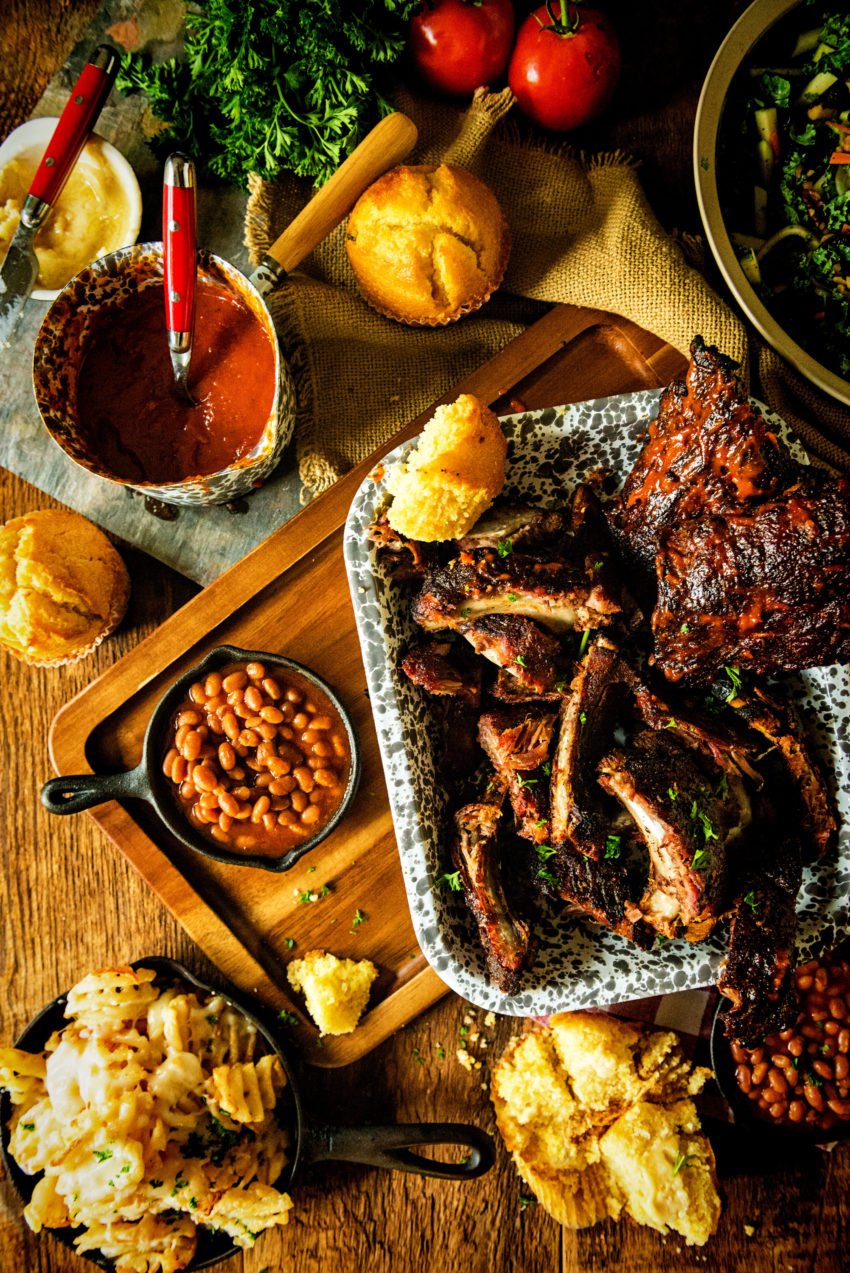 Above shot of a platter filled with dry rubbed smoked ribs, corn bread, beans, and fries. 