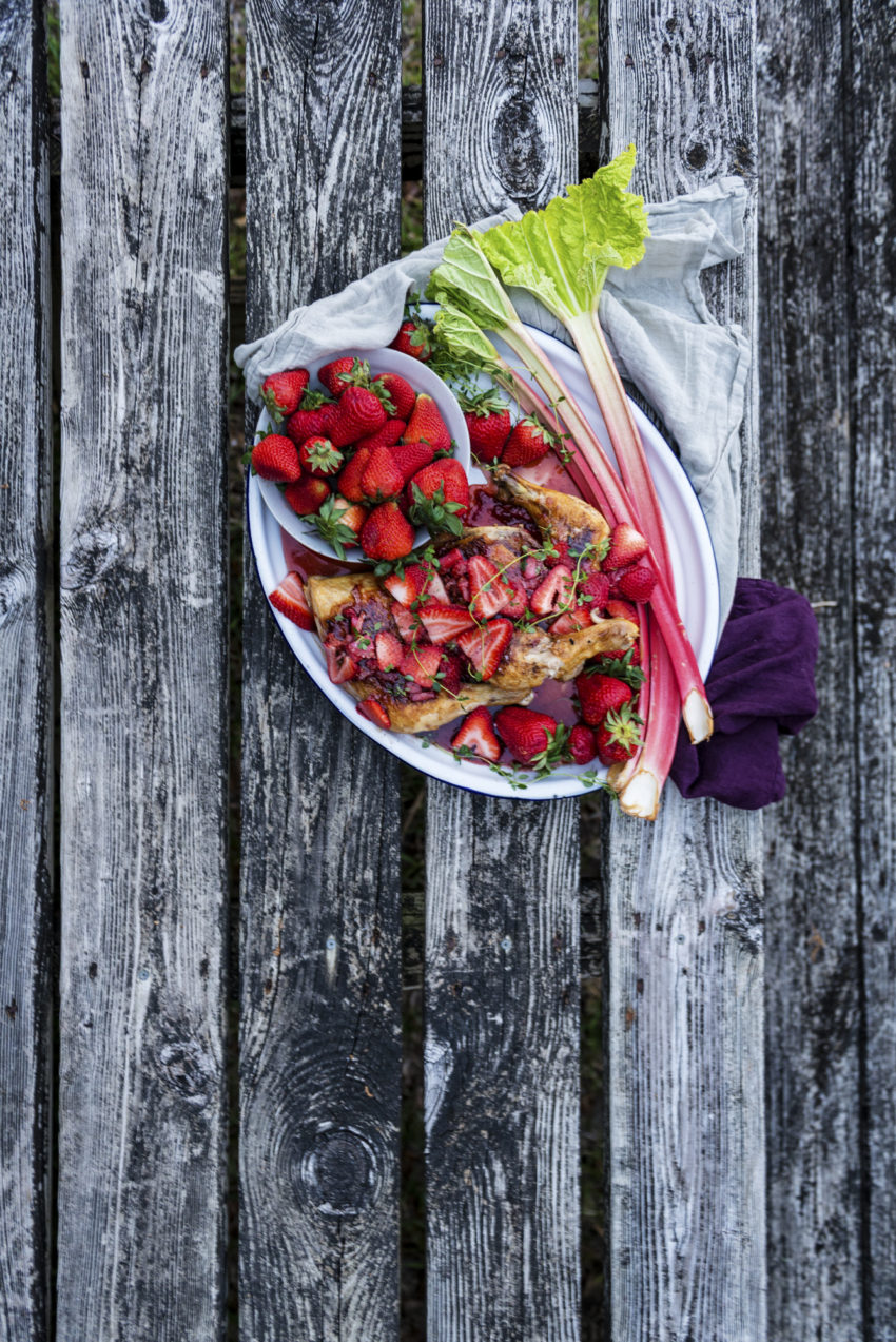 Overhead shot of cast iron chicken plated with glaze and fruits. 