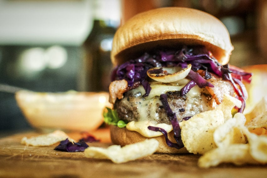 Thick Irish Brat Burger with cabbage braised in beer, onions, bacon, and chips 