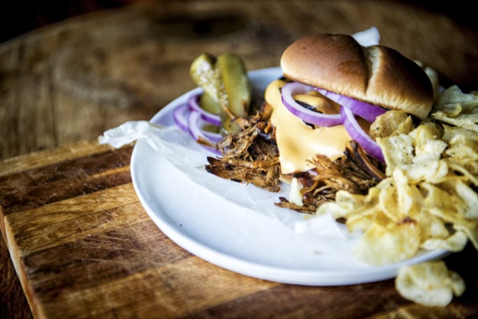 Pulled Pork sandwich on a plate with chips and pickles | Kita Roberts GirlCarnivore.com