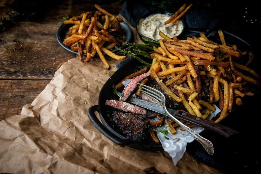 Steak Frites on a cast iron platter with rosemary duck fat fries. This is a meal you're gonna rave about!