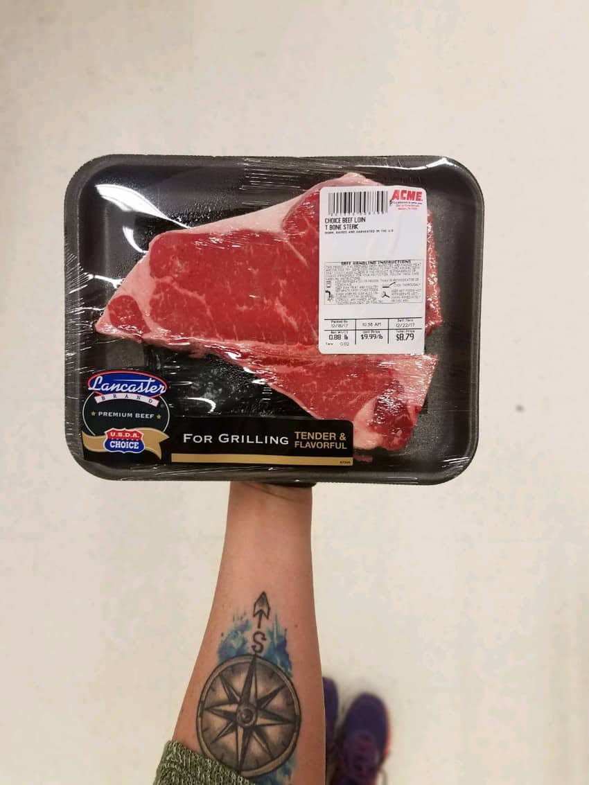 A person holding a piece of steak with meat labels.