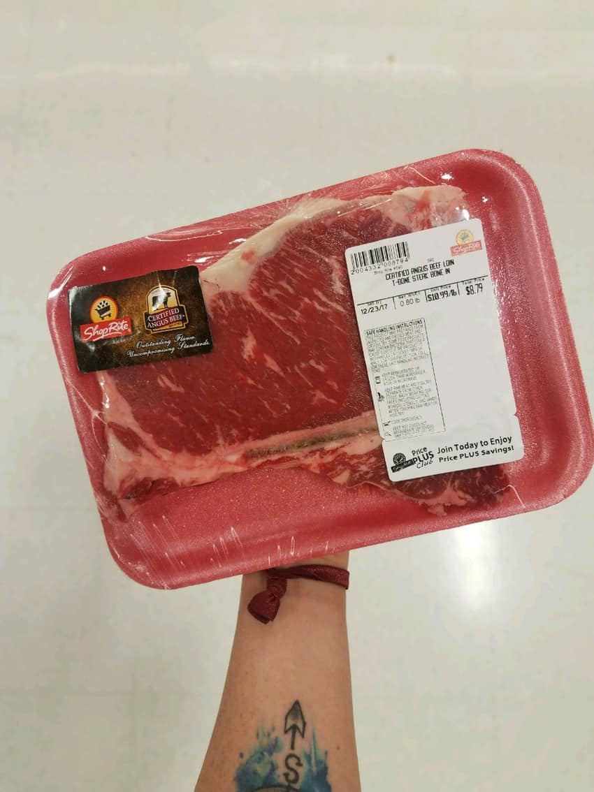 A person holding a red tray with a labeled piece of meat.