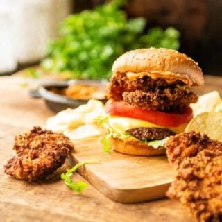 A surf and turf burger on a wooden cutting board.