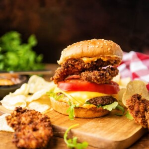 A surf and turf burger on a wooden cutting board.