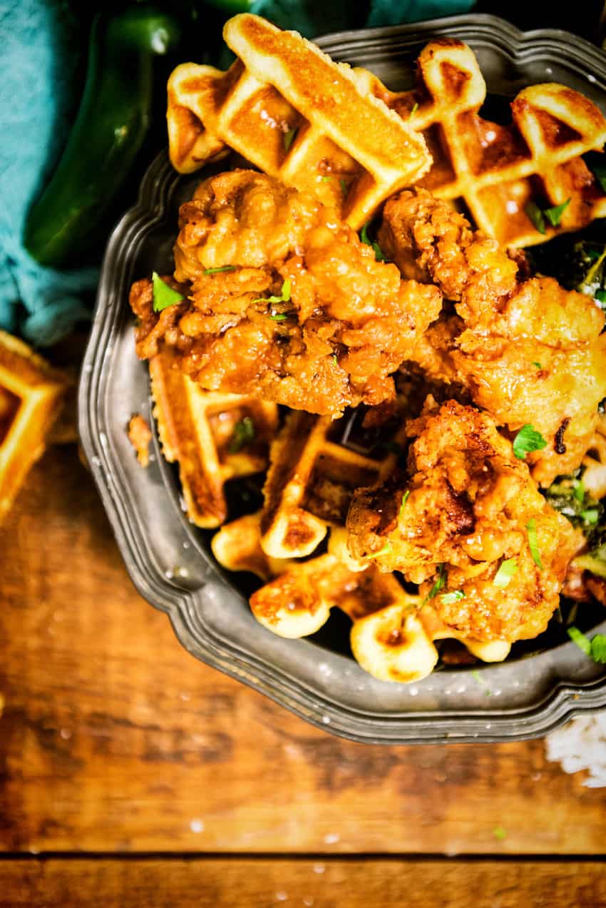 Overhead shot of glistening fried chicken on top of savory waffles. 