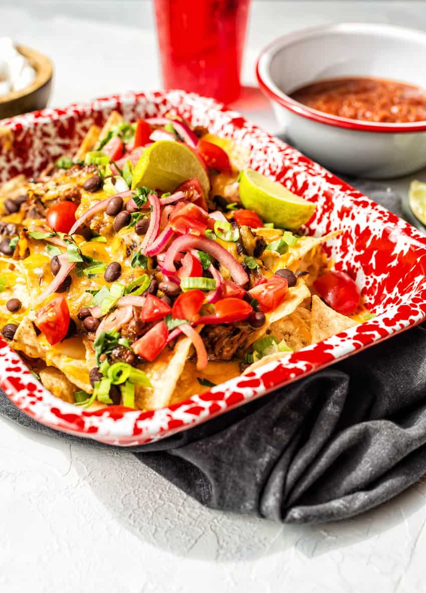 Layers of red onions, scallions, beans, and cheese smother the shredded beef at the center of these nachos.