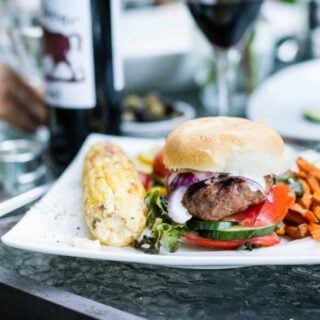 A plate with a lamb burger and corn.