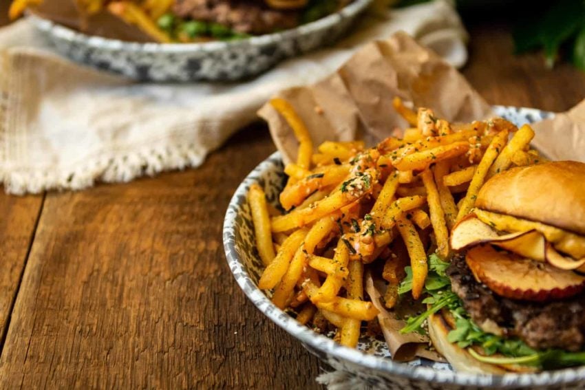 Burger and fries in a plate on a wooden table