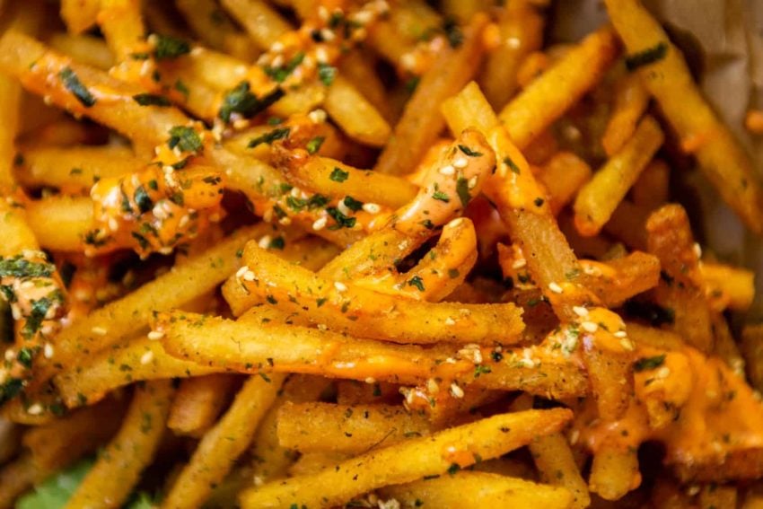 close up fries with furikake, salt and sriracha sauce.