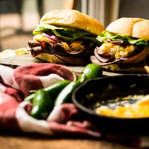 Two roast beef burgers are sitting on a wooden table.