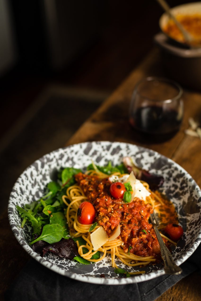 Easy sauce with tons of beef over pasta and fresh salad greens. Garnished with blistered cherry tomatoes and parmesan cheese